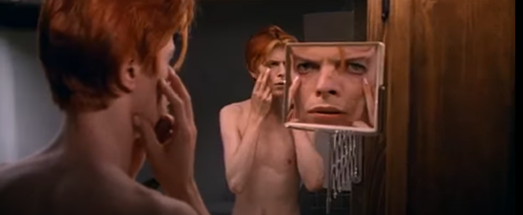 A man holding his face in front of a mirror