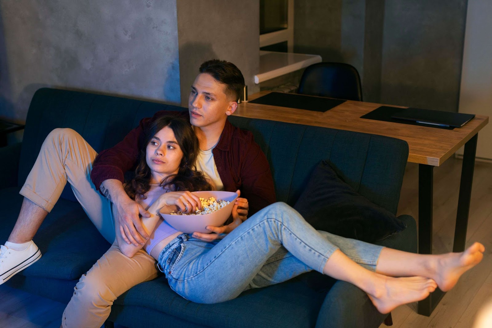 A couple watching TV and eating popcorn