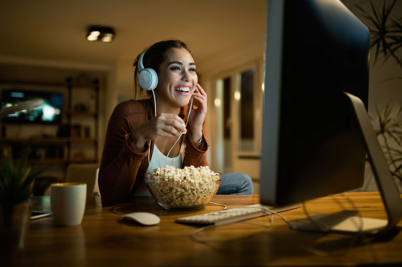 Happy woman eating popcorn and watching movie on computer