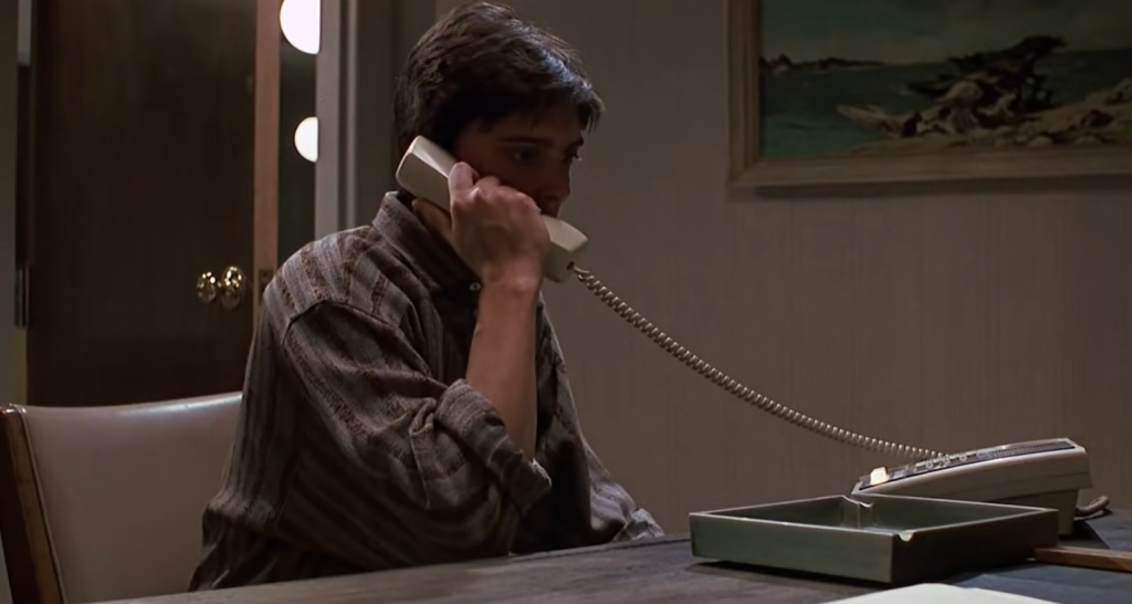 man in a striped shirt making a call and sitting at the table