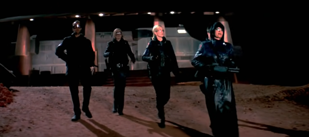 four persons in black clothes with weapons go from the building
