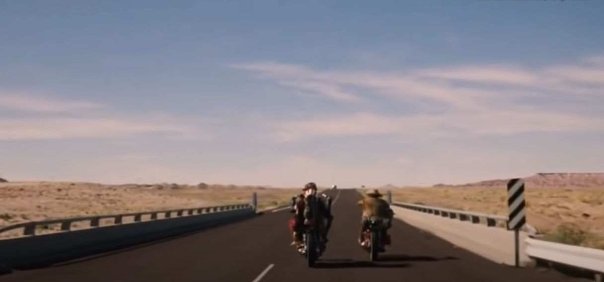 Two motorcycles riding on a deserted highway