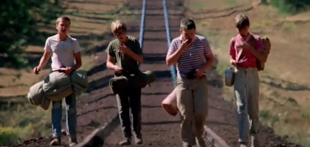 Four children walking on a railroad track