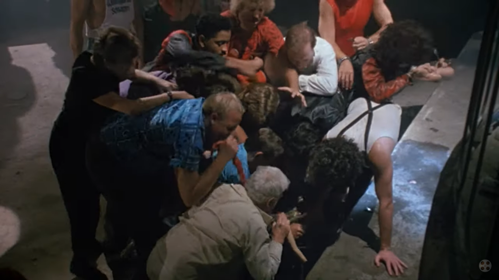 a crowd of people that attack a person lying down on the floor