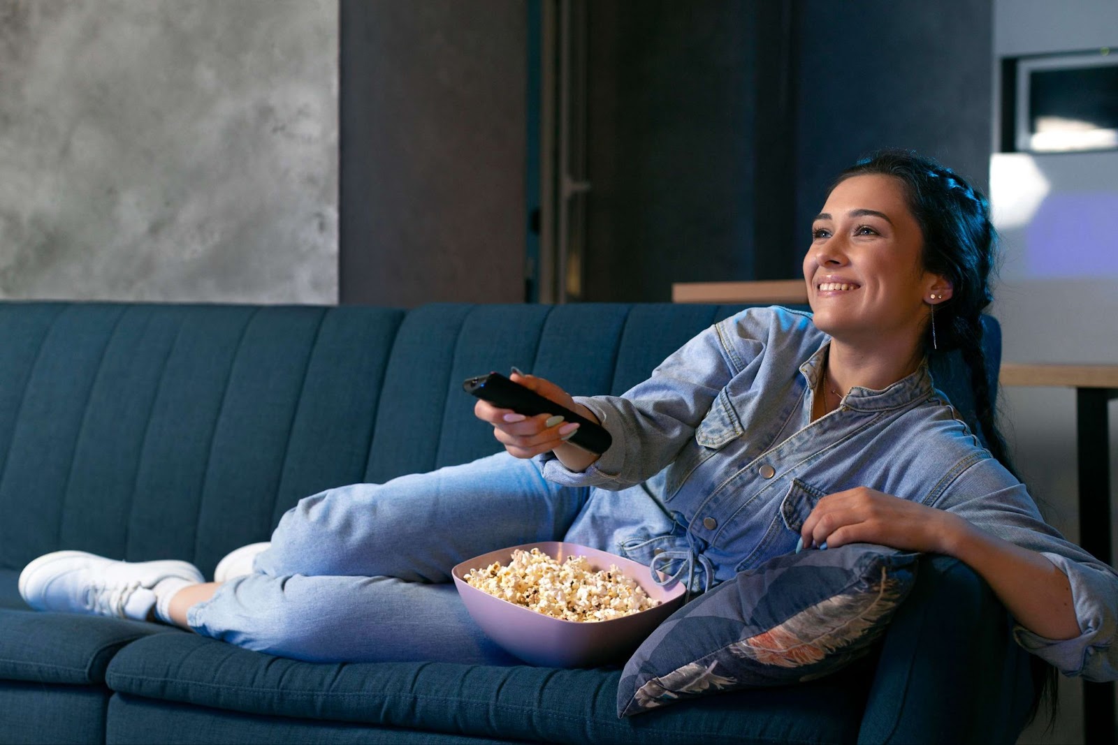 A woman eating popcorn and watching TV